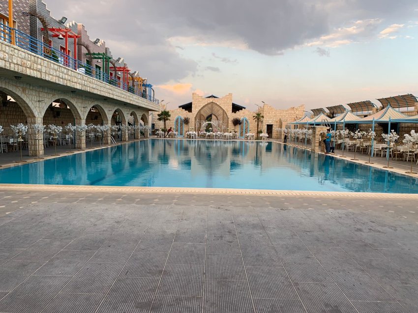 Large swimming pool alongside an arched building and tiled terrace